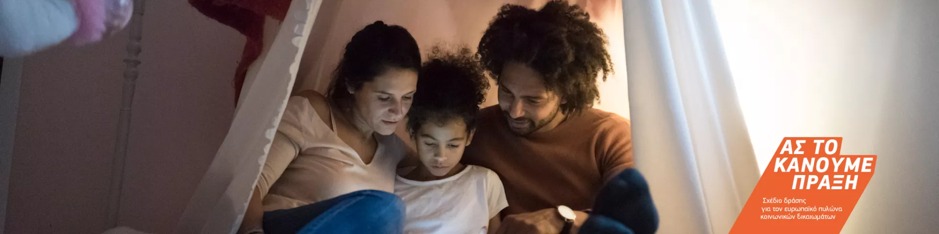 Νέοι γονείς περνούν ποιοτικό χρόνο με το παιδί τους καθισμένοι κοντά ο ένας στον άλλον κάτω από μια αυτοσχέδια σκηνή στο υπνοδωμάτιο του παιδιού.