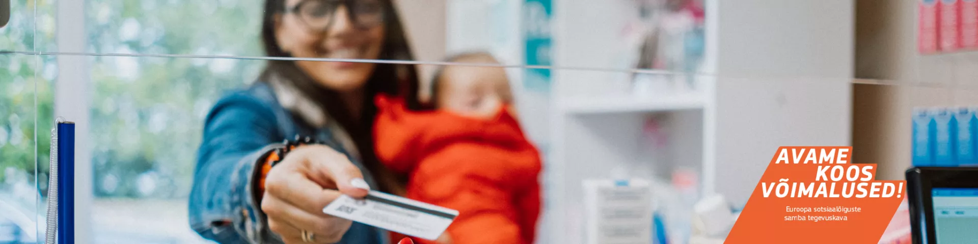 Naine süles oleva lapsega apteegis kaardiga makseid tegemas