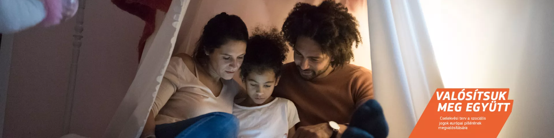 Fiatal szülők minőségi időt töltenek együtt gyermekükkel, egy sátorszerű kuckóban a gyermek hálószobájában. 