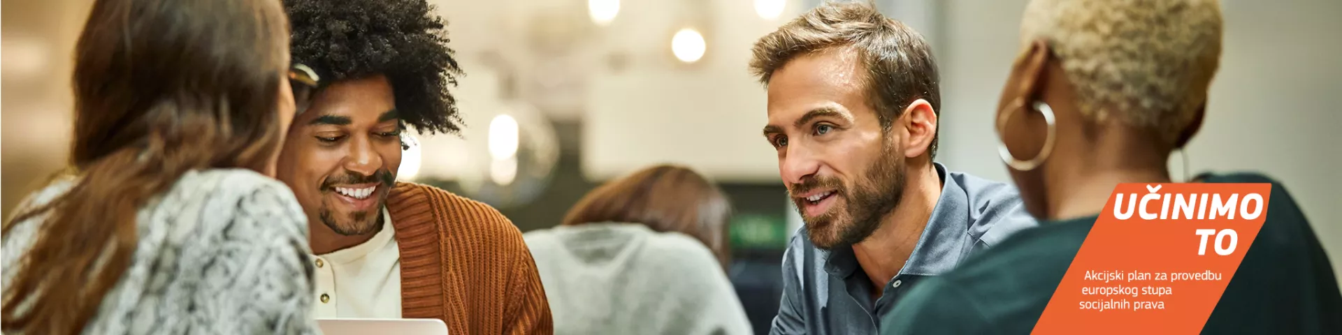 Raznolika skupina mladih osoba sjedi i razgovara.  